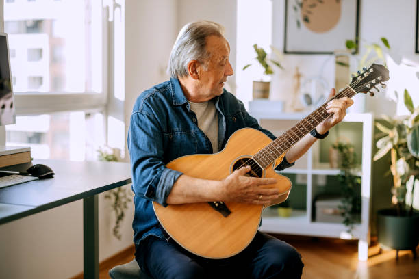 istock Senior man playing guitar at home 2184706932