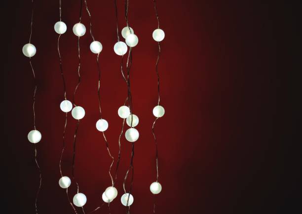 Glowing electric garland on red background in the dark