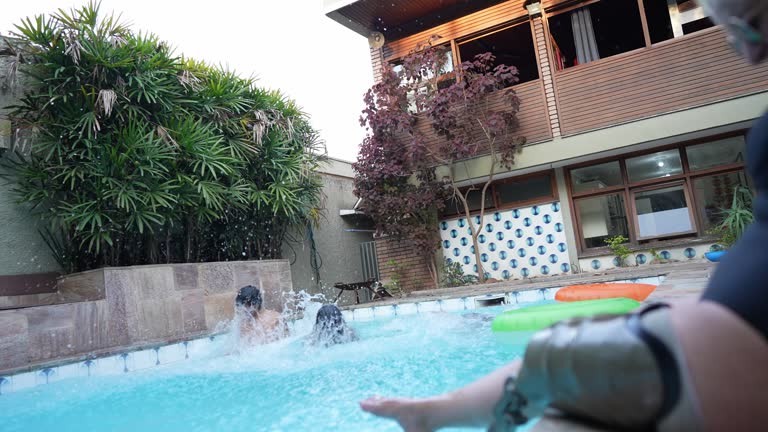 Young friends jumping in the pool during a party at home - including a woman with an amputated leg