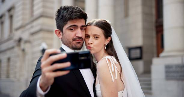 istock Couple, selfie and celebration with wedding in city, love or happy for commitment, memory and post on web. People, man and woman for marriage, event or funny face with smile on social media 2184712077