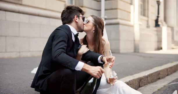 istock Wedding, kiss and couple in city with alcohol for ceremony, celebration or commitment with embrace. Romance, love and man and woman in town with champagne for promise, affection and marriage at court 2184712124