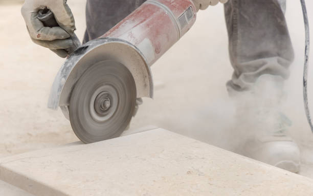 istock Craftsman in grey work clothes and helmet cutting marble piece during construction 2184715426