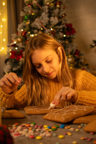 istock A girl is decorating gingerbread house with icing for Christmas. 2184718358