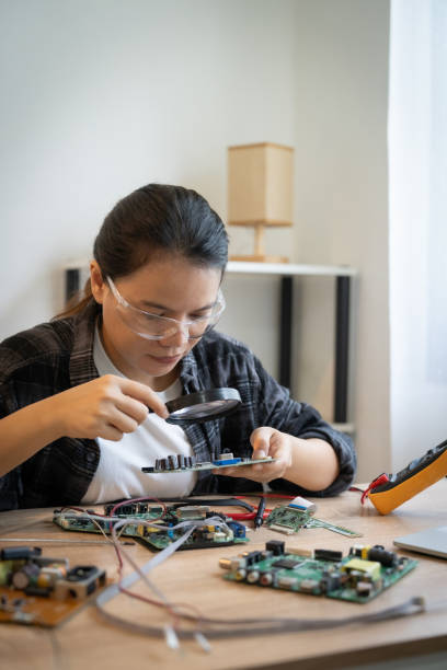 istock A woman is looking at a small electronic device with a magnifying glass. She is focused on the device and she is examining it closely. Concept of curiosity and attention to detail 2184718513