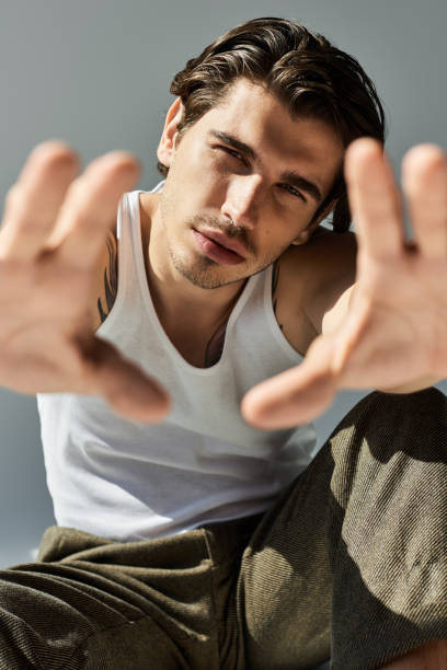 A handsome young man showcases his unique style while posing gracefully in a chic studio space.