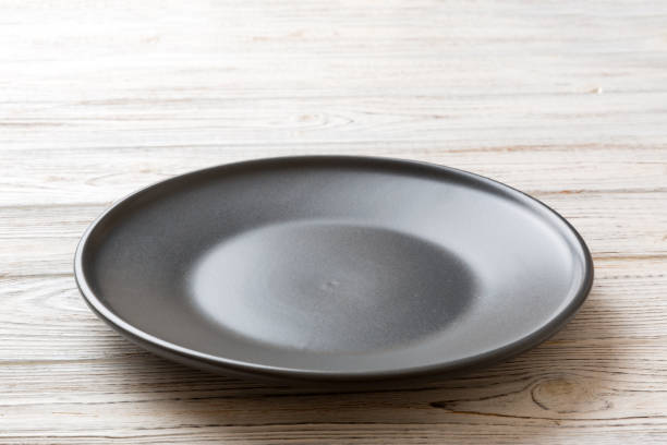 istock Perspective view of empty black plate on wooden background. Empty space for your design 2184726975