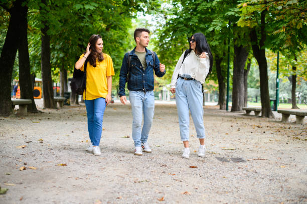 istock Three young adult students walking and talking in a park 2184728015