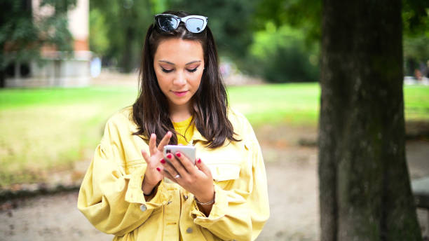 istock Young woman using smartphone in a park 2184729369