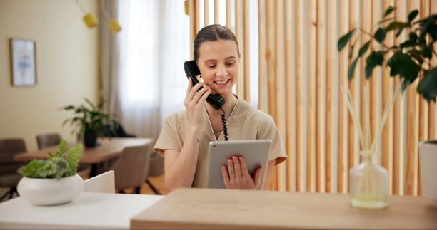 phone call, spa and woman at reception with tablet checking website for online booking schedule. consultant, receptionist or girl at front desk on telephone, digital app or appointment at hotel salon - receptionist bildbanksfoton och bilder