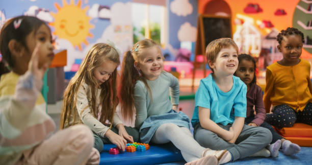 istock Cheerful Daycare Teacher Using Gaming and Acting Methods to Teach Multiethnic Kids Alphabet in Kindergarten. Small Cute Boys and Girls Getting Basic Reading and Writing Skills, Learning Alphabet 2184734681