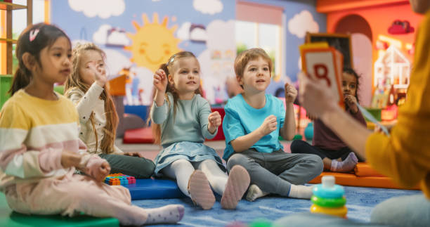 Cheerful Preschool Educator Playing and Creatively Studying with Multiethnic Kids in Kindergarten. Small Adorable Children Getting Basic Reading and Writing Skills, Learning Alphabet