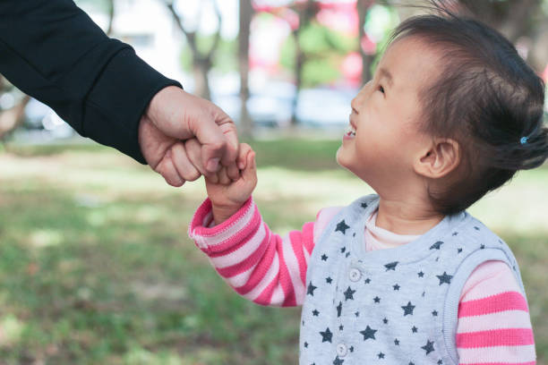 istock An Asian father is holding his daughter's hand while walking in the park. 2184735067
