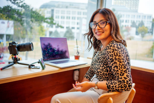 A young female content creator recording a video about stock exchange online  in a modern cafe setting