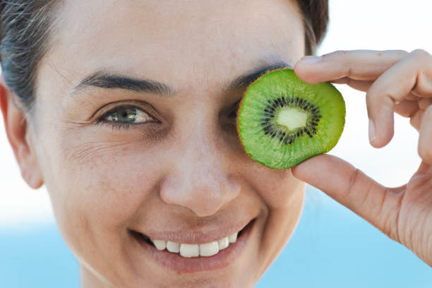 istock Woman Holding Kiwi Slice Over Eye 2184736711