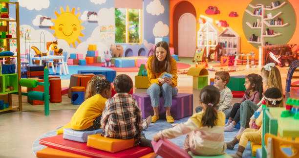 istock Happy Kindergarten Pedagogue Having a Conversation with Kids, Using Enthusiastic Teaching Methods in a Modern Colorful Kindergarten. Female Educator Stimulating Linguistic and Social Skills 2184738055