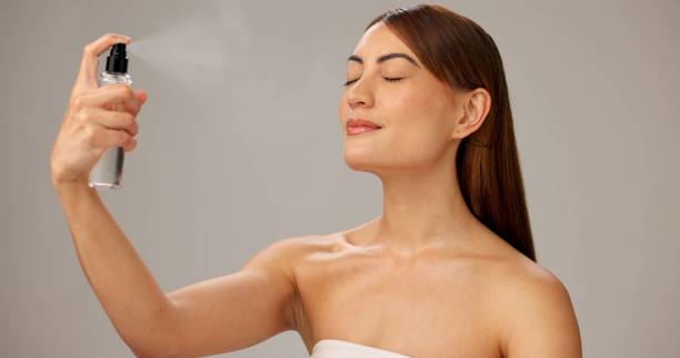 istock Woman, studio and makeup with setting spray for beauty, glow and cosmetics on gray background. Female person, beautician and eyes closed with face mist for application, foundation and blending 2184739224