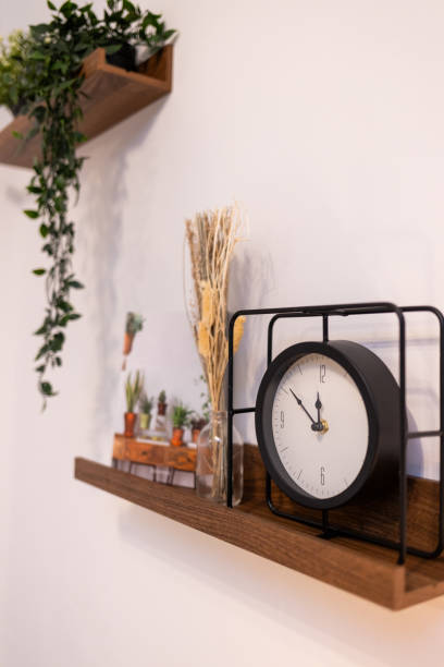istock the clock stands on a wooden shelf against a white wall 2184740652