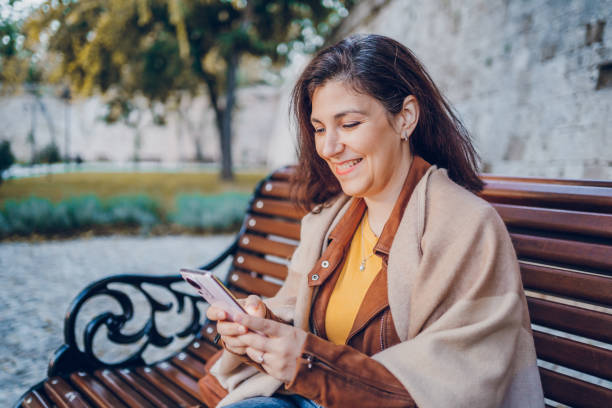 istock Women sitting and using her phone at the park 2184746688