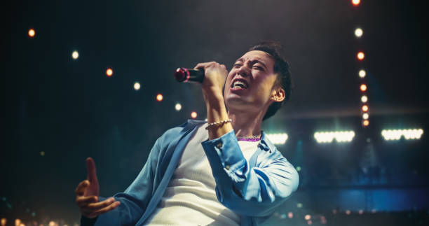 Pop Concert with a Romantic Atmosphere: Young Talented Musician Performing Live on Stage in Front of Screen with Pink Visual Effects. Creative Cinematic Footage with Singer's Silhouette