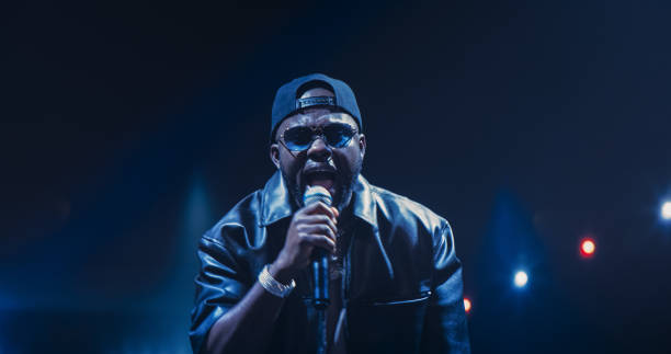 istock Creative Rap Artist Performing a Hit Song on Stage with a Striking Female Dancer, Inspiring a Large Audience in a Colorful Neon Concert Setting with Cinematic Lighting and Animated LED Screen 2184753444