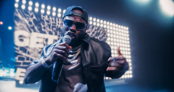 istock Creative Rap Artist Performing a Hit Song on Stage with a Striking Female Dancer, Inspiring a Large Audience in a Colorful Neon Concert Setting with Cinematic Lighting and Animated LED Screen 2184753474