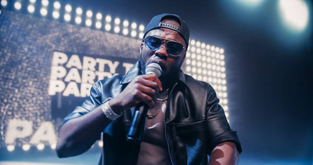 istock Creative Rap Artist Performing a Hit Song on Stage with a Striking Female Dancer, Inspiring a Large Audience in a Colorful Neon Concert Setting with Cinematic Lighting and Animated LED Screen 2184753497
