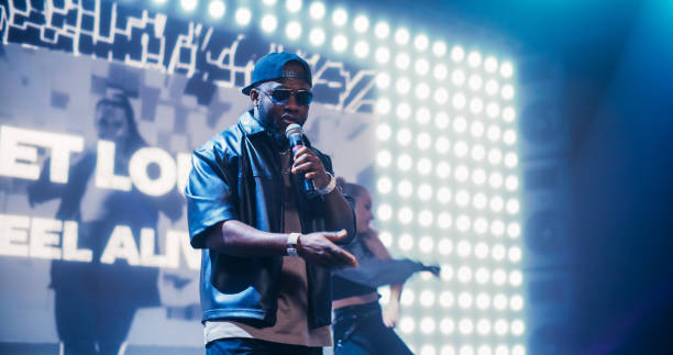istock Rap Artist Performing on a Vibrant Stage with an Energetic Female Dancer, Entertaining a Large Audience in a Concert Hall. Performer Dancing a Hip Hop Choreography Routine in Smoke 2184753650