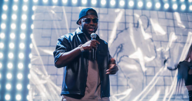 istock Rap Artist Performing on a Vibrant Stage with an Energetic Female Dancer, Entertaining a Large Audience in a Concert Hall. Performer Dancing a Hip Hop Choreography Routine in Smoke 2184753671