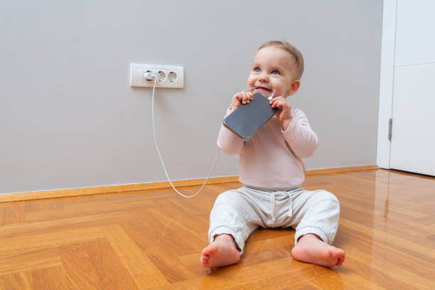 istock Baby chewing on cell phone charging cable. Risk of electric shock 2184755003
