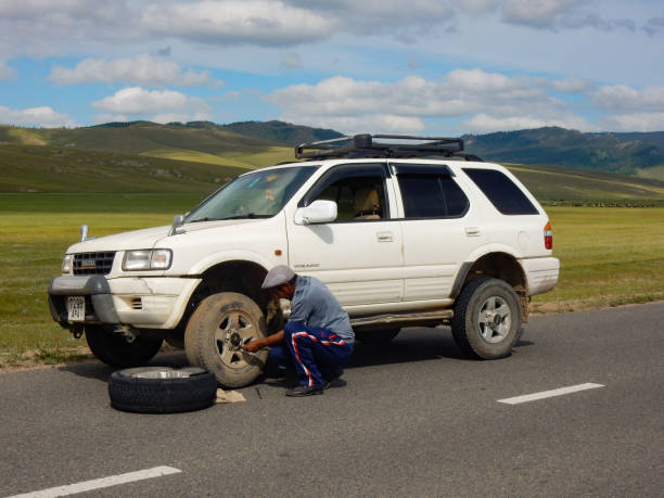Driver changes a flat tyre on his four wheel drive vehicle in Mongolia