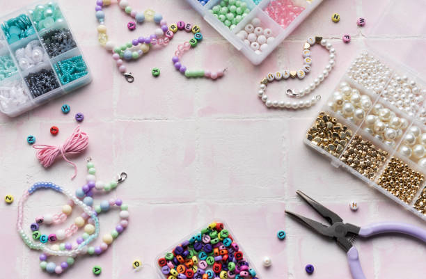 istock Colorful beads and jewelry making tools arranged on pink tile surface 2184759189