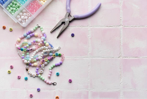 istock Colorful beads and jewelry making tools arranged on pink tile surface 2184759204