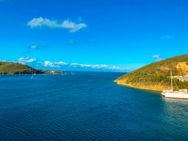 Deep blue ocean cove with sailboats along side island mountain