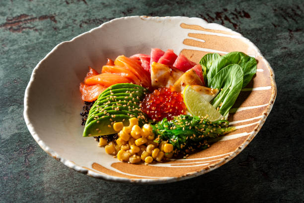 A bowl of poke with raw fish slices, avocado, corn, greens, and rice, garnished with sesame seeds. The vibrant colors and fresh ingredients make it a visually appealing and healthy meal option.