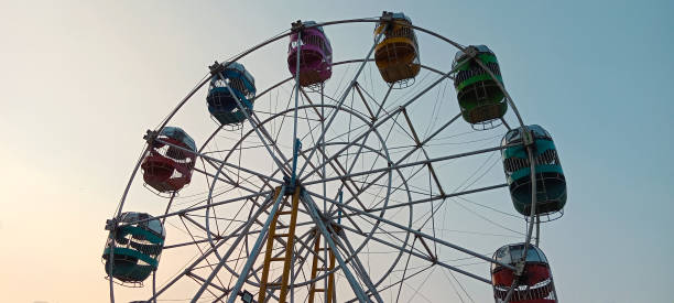 istock a Ferris wheel with a vibrant array of multi-colored passenger cabins, including red, green, blue, yellow, and pink. with dusk dawn coloured sky 2184762192