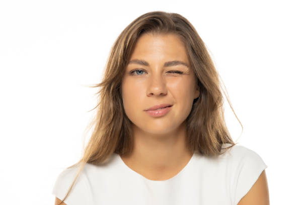istock Portrait of young woman with a light makeup winks on a white studio background 2184762684