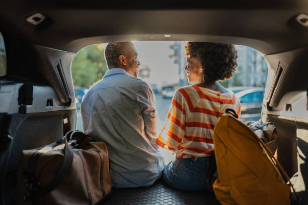 istock Couple sits in car trunk relaxing before trip. 2184765596