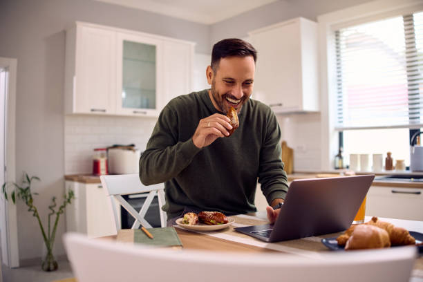 istock Happy man working on laptop while having a breakfast in the kitchen. 2184769990