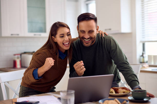 istock Happy couple celebrating while paying their bills online at home. 2184770062