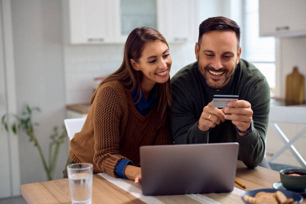 istock Happy couple using credit card while shopping on the internet at home. 2184770078
