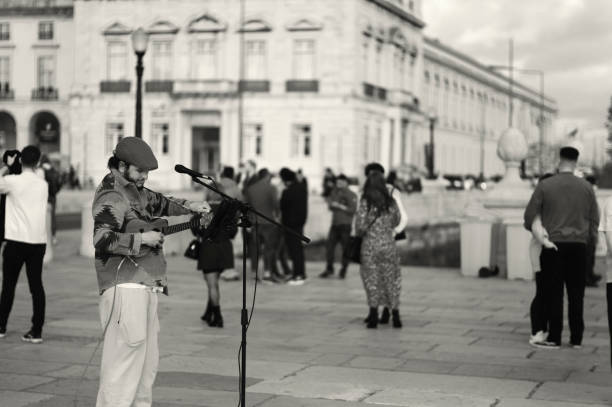 Lisbon, Portugal - November 11, 2023: A street musician tunes his ukelele at the Praça do Comércio square in Lisbon downtown.