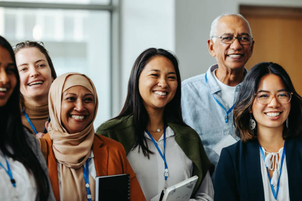 Smiling multiethnic group of happy professionals representing diverse ages gathered at a corporate event displaying positive emotions and unity.