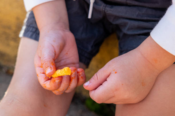 A child eats cheese puff snacks with cheese covered fingers
