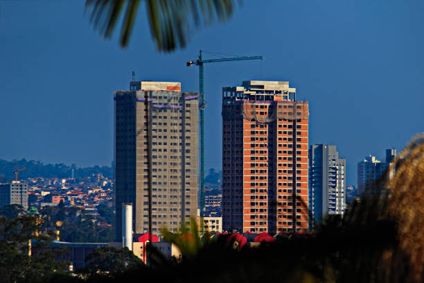 city ​​skyline on a sunny day with two apartment towers under construction - MOGI DAS CRUZES,  SAO PAULO, BRAZIL.