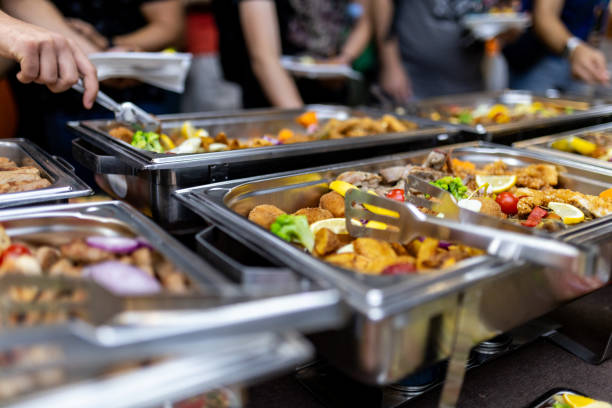 istock People enjoying a buffet meal with various dishes at a catered event indoors during the evening 2184780971