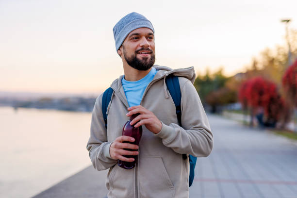 istock Athletic man holding a water bottle by the river at sunrise 2184781489