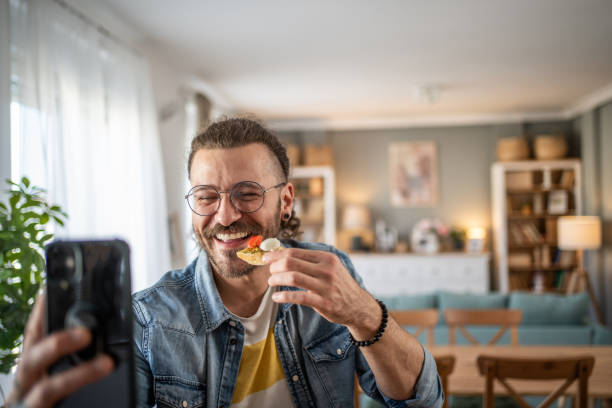 istock Hipster guy captures the moment with bruschetta in hand while taking a selfie 2184782049