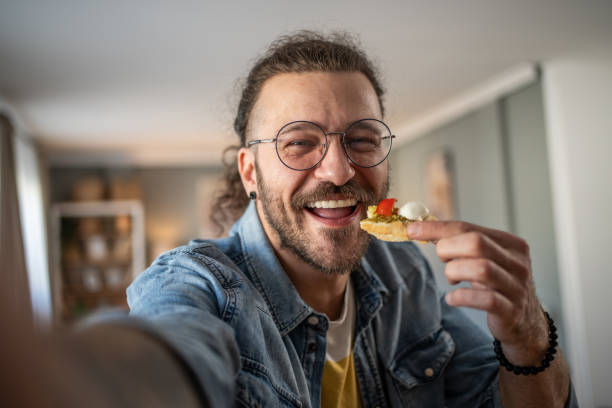 Hipster guy captures the moment with bruschetta in hand while taking a selfie