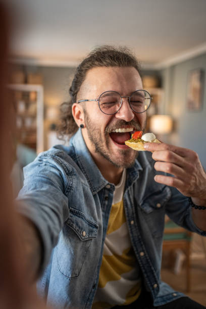 istock Hipster guy captures the moment with bruschetta in hand while taking a selfie 2184782074