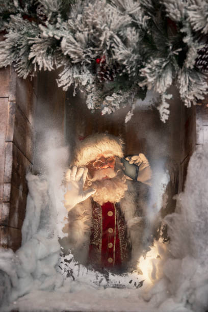 istock Santa Claus using phone behind frosty home window 2184786952